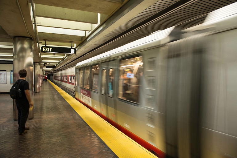 A Muni light rail train arrives in Powell Station with a passenger waiting on the platform.