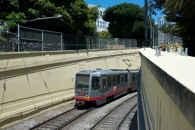 Gray N Judah light rail vehicle emerges from the Sunset Tunnel portal in Cole Valley.