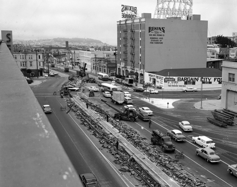 Overhead view looking west on Geary Boulevard at Presidio Avenue of workers removing streetcar tracks from center of roadway. August 15, 1958