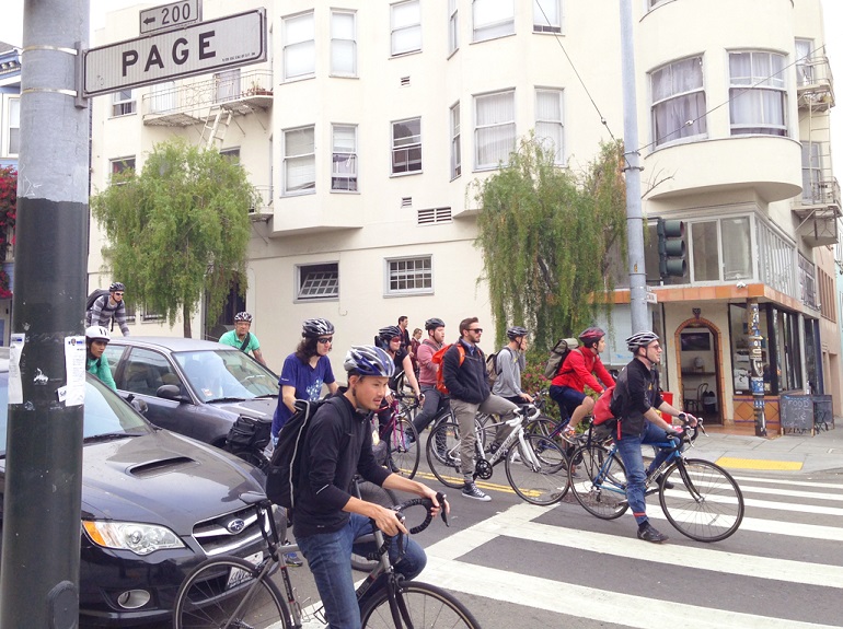 A scene of the Page and Octavia intersection before the bike lane and boxes were added shows people on bikes waiting in the opposite traffic lane and the crosswalk.