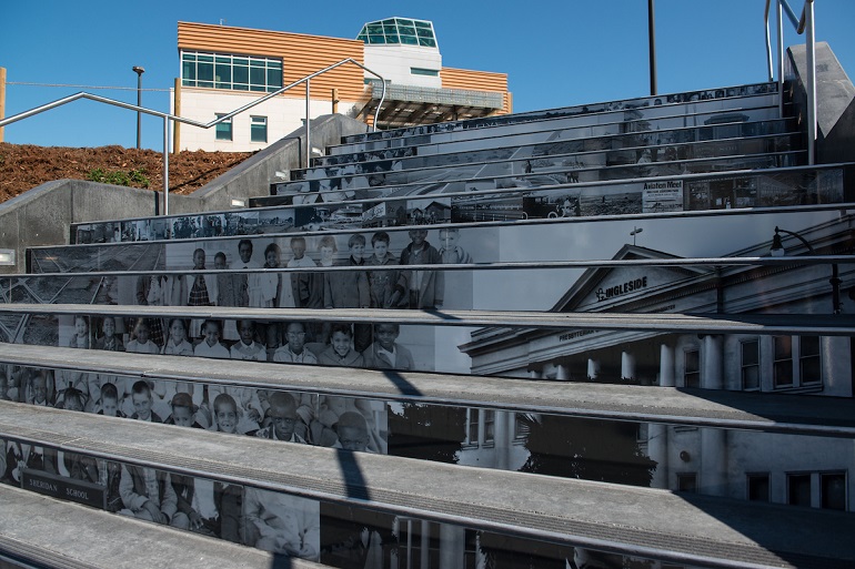 Wide steps with black and white images on the risers with the City College muti-purpose building in the background.