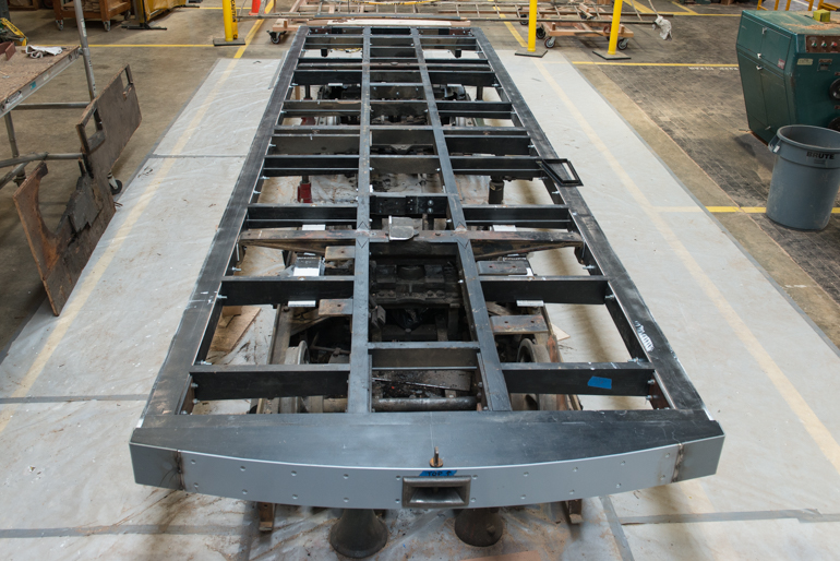 color photo of the frame of cable car 23. The frame consists of various length and thicness wooden beams which are connected together in a lattice using steel "L" shaped and straight brackets.