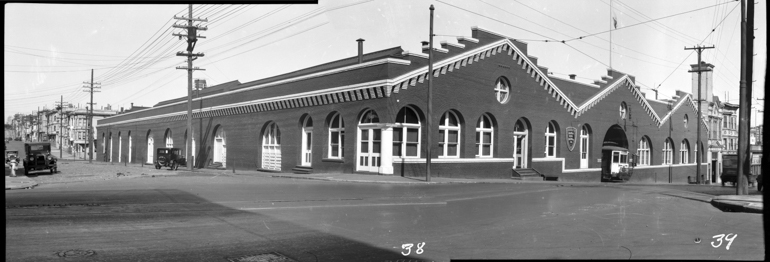 Black and white photo showing large brick building on Oak and Broderick Streets.  Building was used as a storage and repair facility for the Market Street Railway Company, taken October 1928