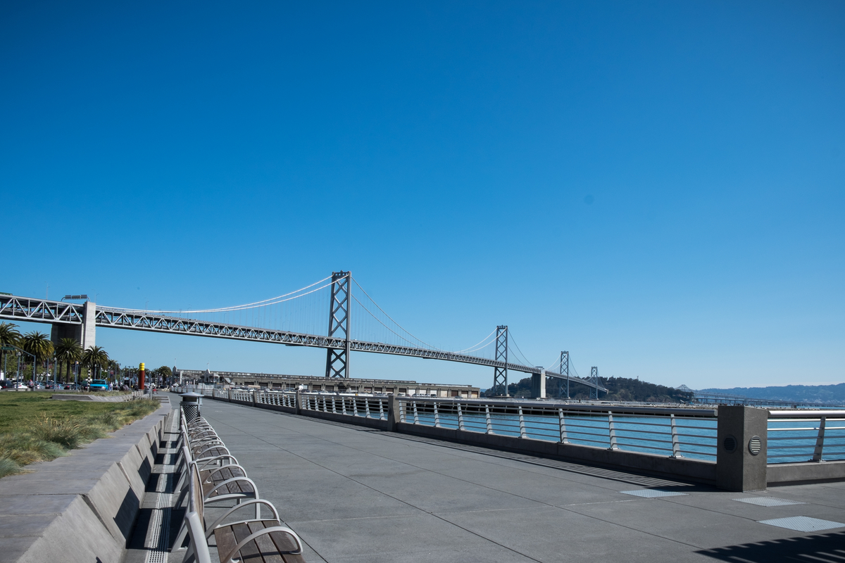 View of the western span of the Bay Bridge from The Embarcadero to Yerba Buena Island with a cloudless blue sky in the background.
