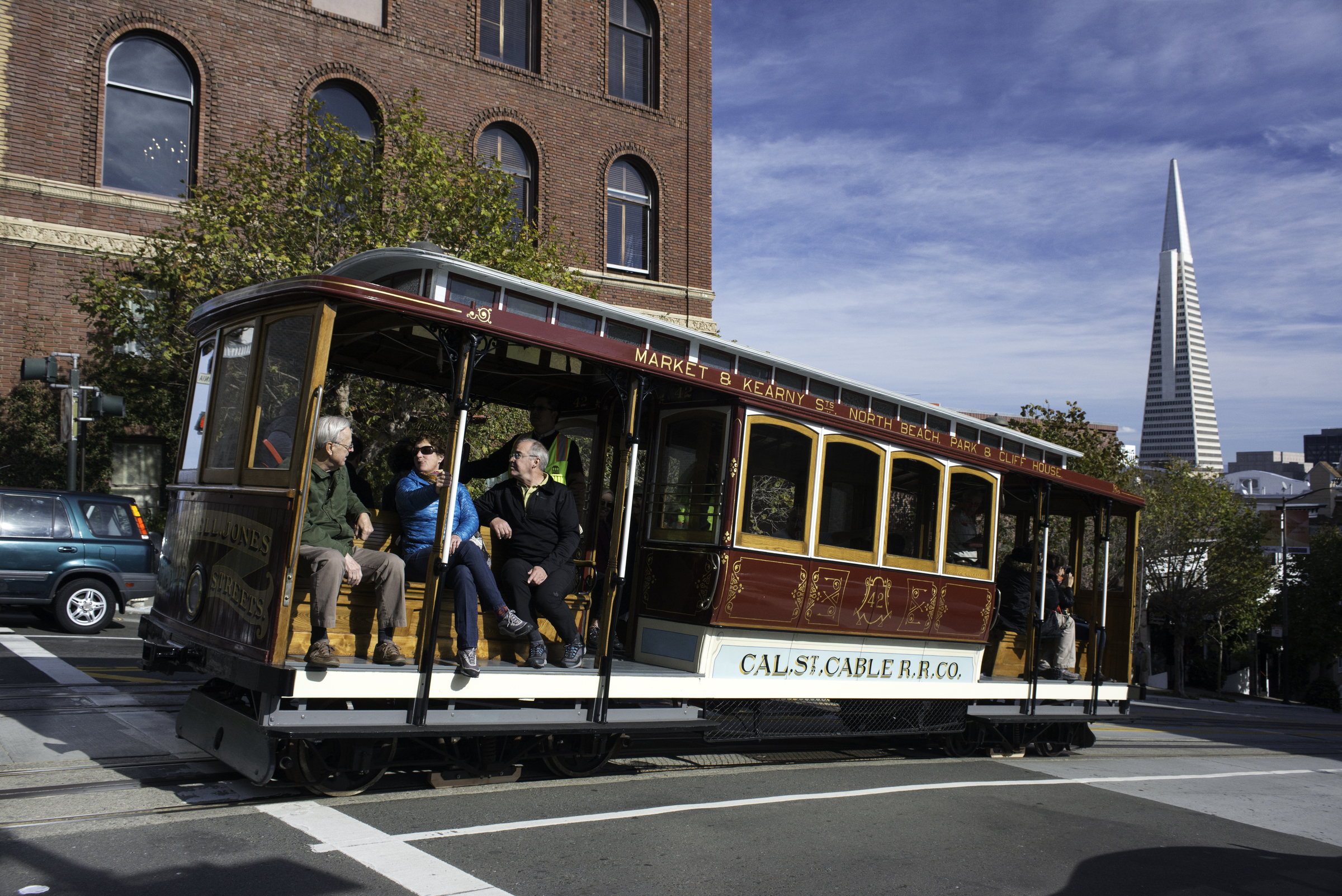 A shiny, refurbished cable car 42 travels west on California Street with the Transamerica Pyramid in the background on the right 