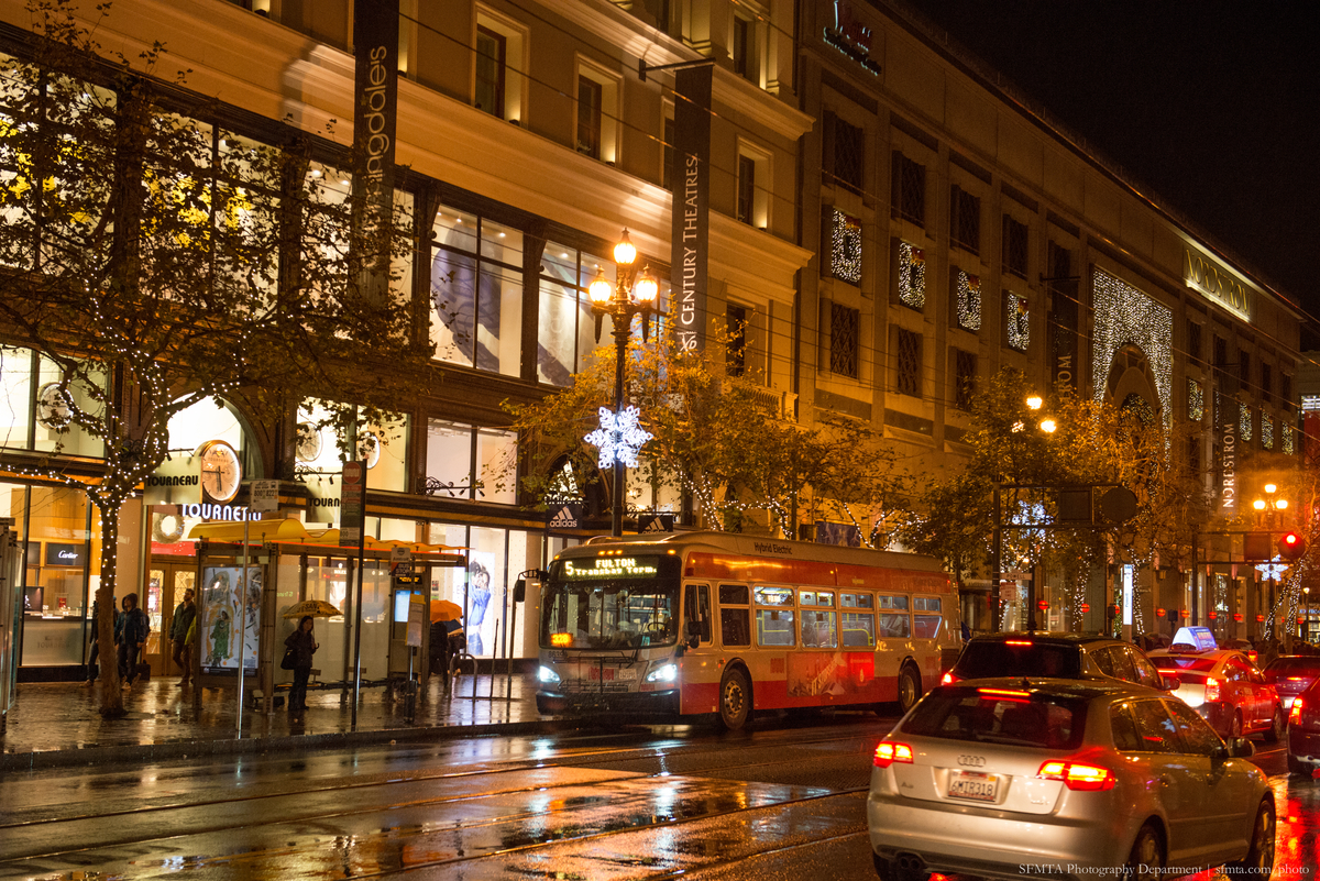 Busy Market Street at night with festive lights on the trees