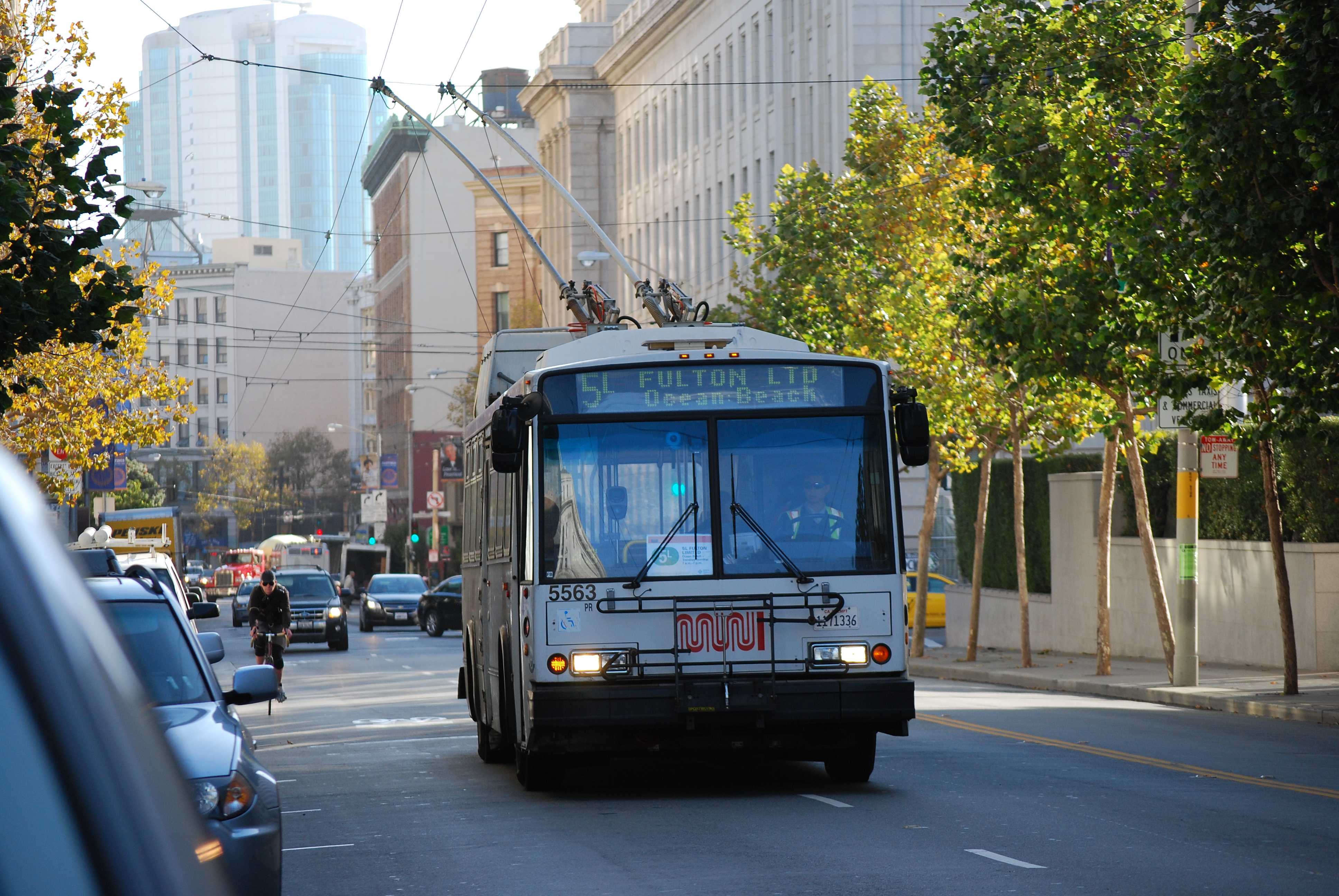 5L Fulton Limited trolley bus travels down McAllister Street with traffic, bicycles and city buildings in the back drop.