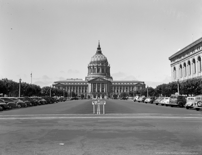 Black and white photo of city hall in 1948 from Fulton and Hyde, the old library is on the right. Cars line the sides of the street, framing city hall.