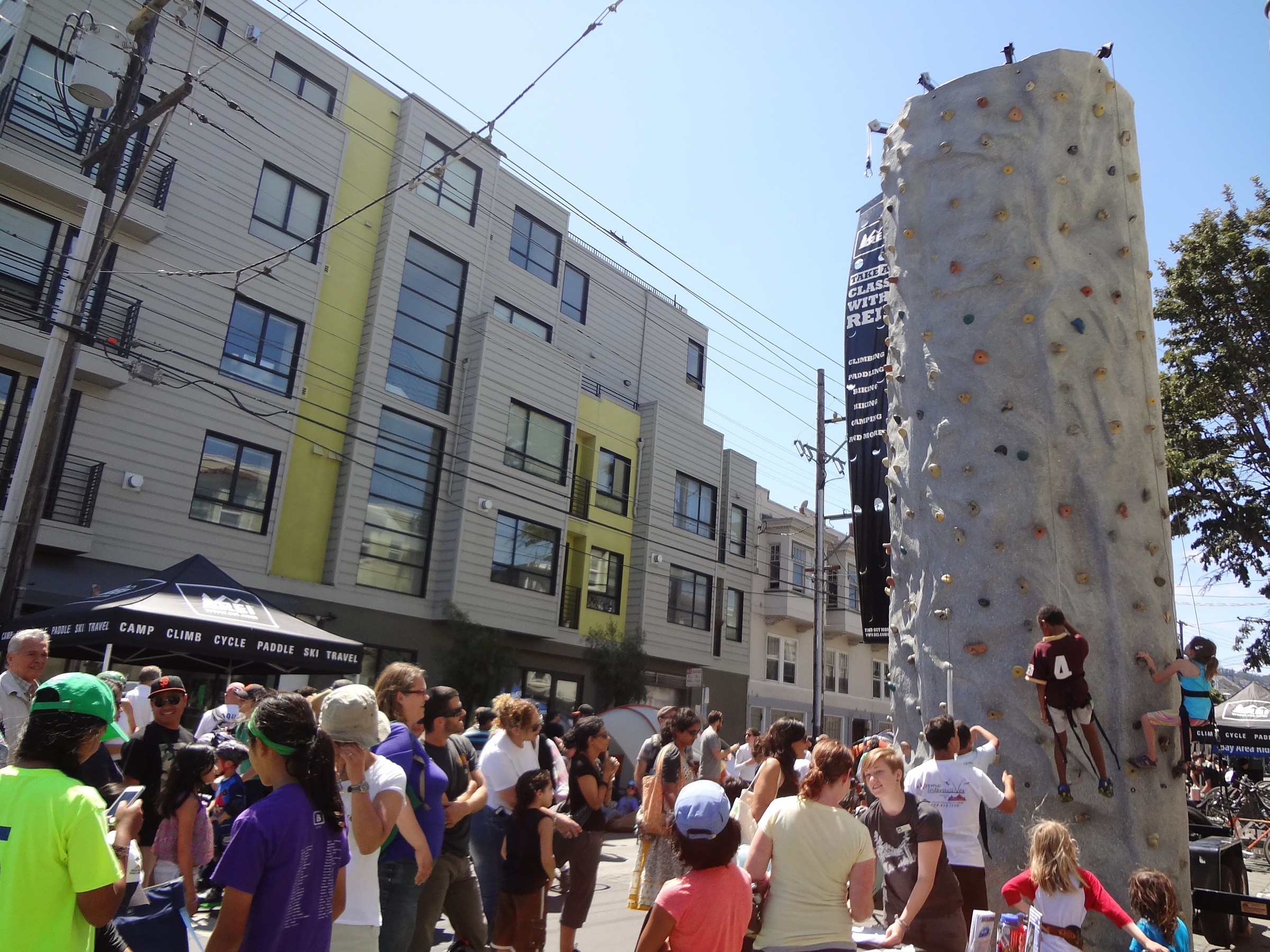 Crowd standing around rock-climbing event at Mission Sunday Streets