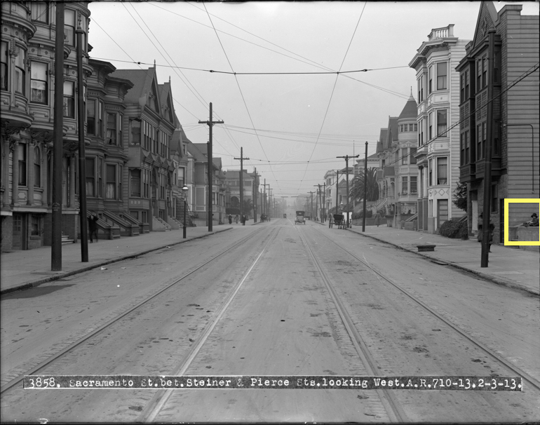 View West on Sacramento Street between Steiner and Pierce Streets from center of road showing streetcar tracks, victorian houses, overhead wires, and an old car in the distance.  Taken February 3, 1913