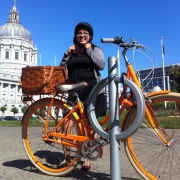 picture of cyclist putting on her helmet while her bike is parked