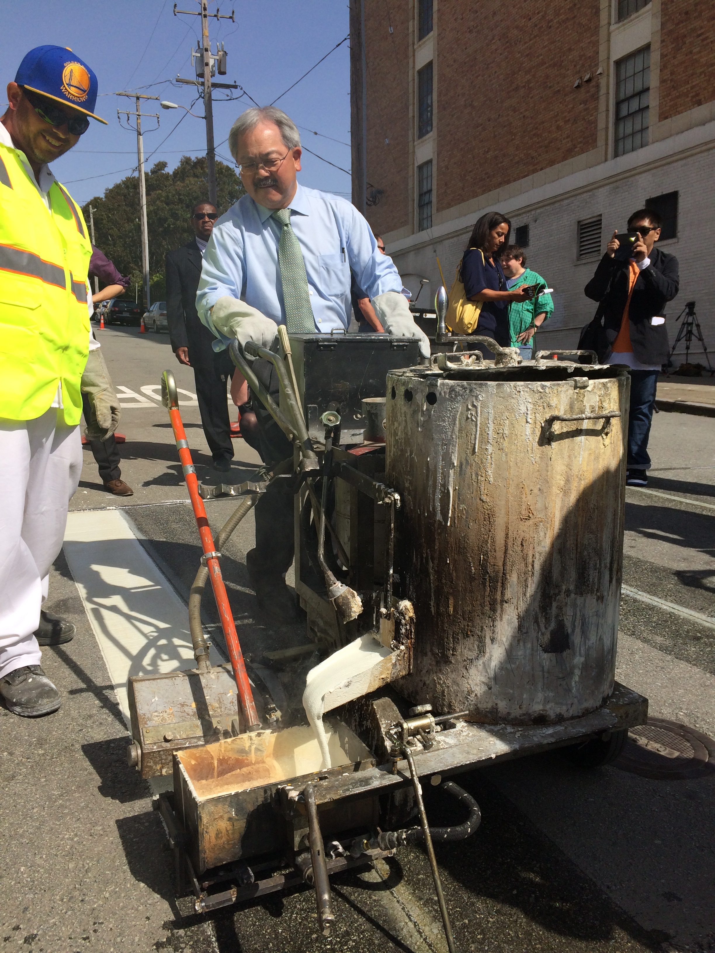 Mayor Lee and paint crew member lay down first pass of paint for crosswalk at Emerson and Geary.