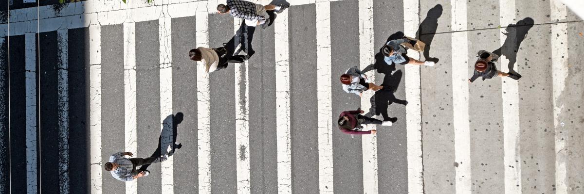 Pedestrians on 5th Street and Mission Street seen from above in a birds eye view as the cross the a zebra-striped crosswalk