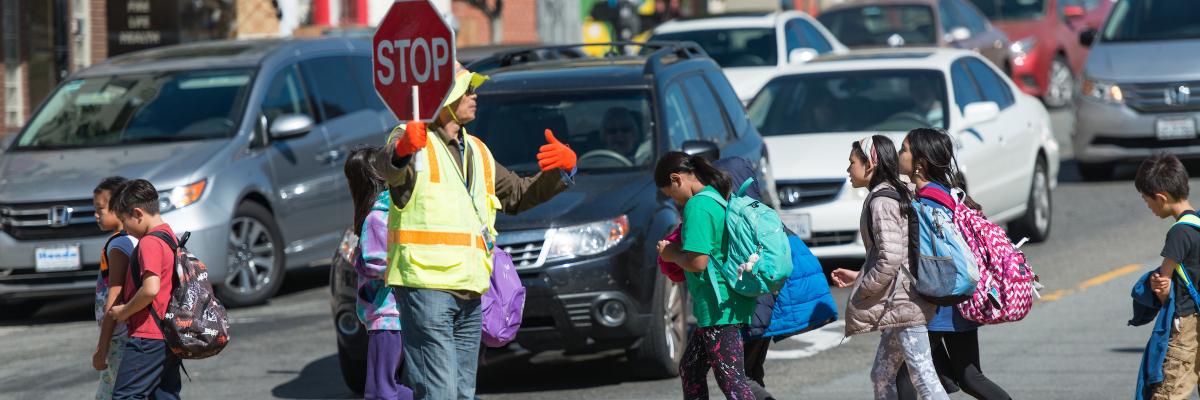 Picture of a crossing guard helping children cross the street
