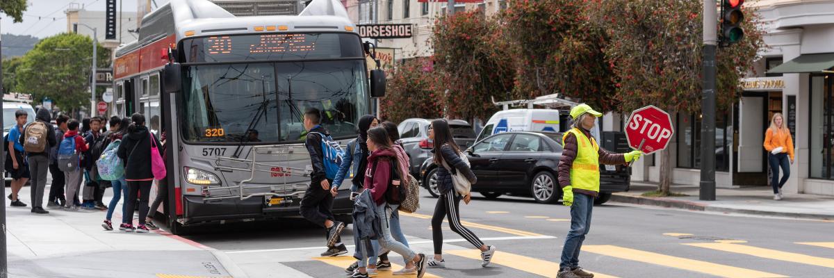 Students crossing the street to catch a waiting Muni bus