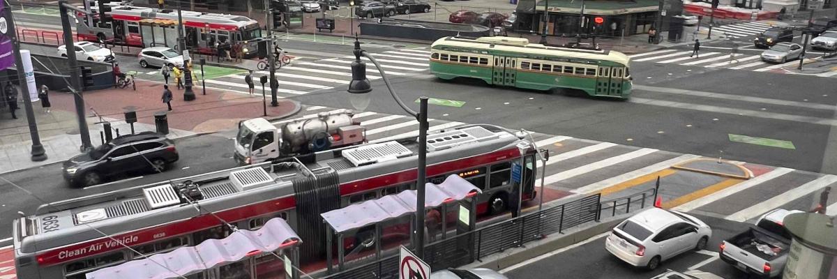 Intersection of Market and Van Ness filled with Muni vehicles, red carpet lanes, bus rapid transit, bikers and pedestrials