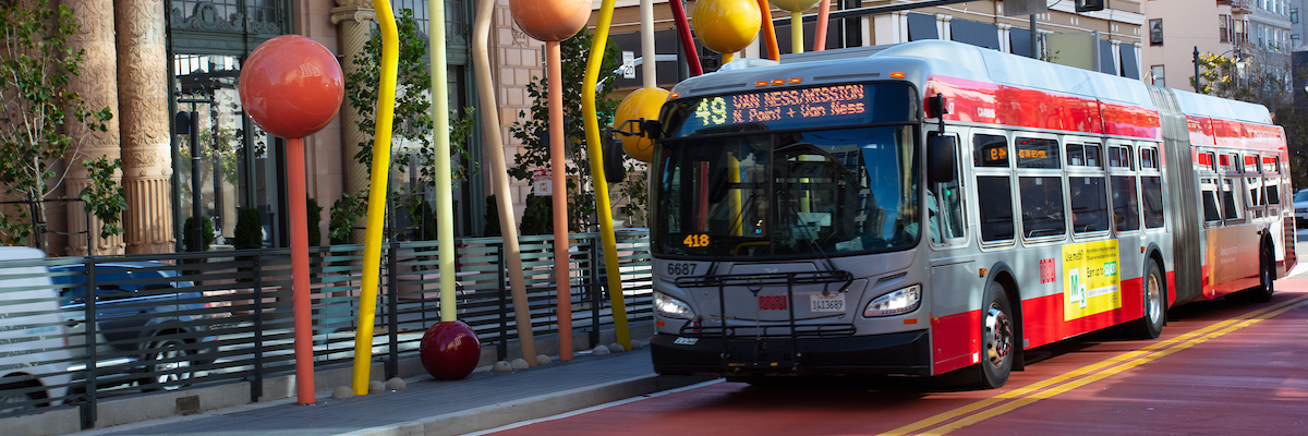 A bus driving down the new red bus rapid transit lane on Van Ness in front of a public art installation