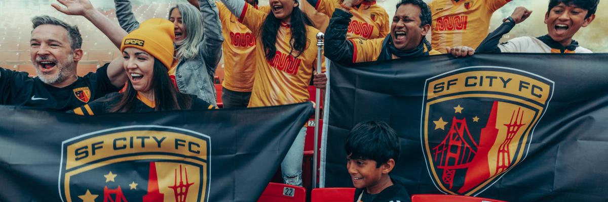 Cheering soccer fans wearing SF City Jerseys featuring the Muni worm