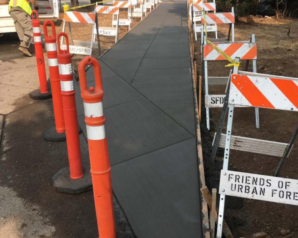 Concrete path, still wet, with construction barriers surrounding