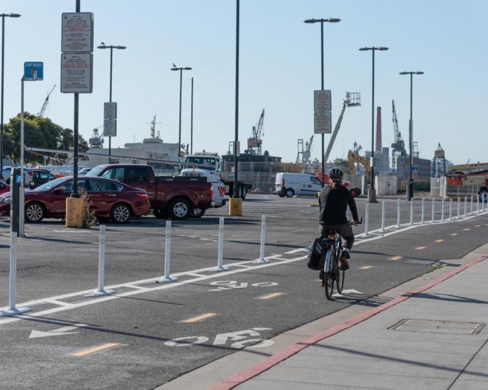 A bicyclist in a two-way protected bikeway buffered with plastic delineators