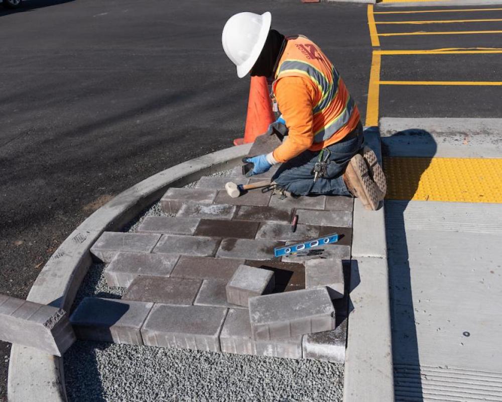 Image of worker installing pavers at a new median refuge at Geary and Steiner