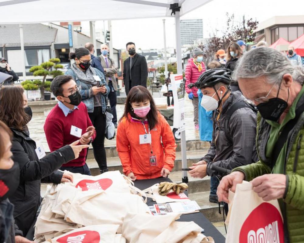 SFMTA staff hand out Muni bags to guests at the Geary Rapid ribbon cutting event