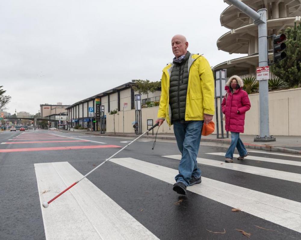 Image of Lou Grosso, a blind member of the Geary Community Advisory Committee, crossing the street at the new Buchanan crosswalk