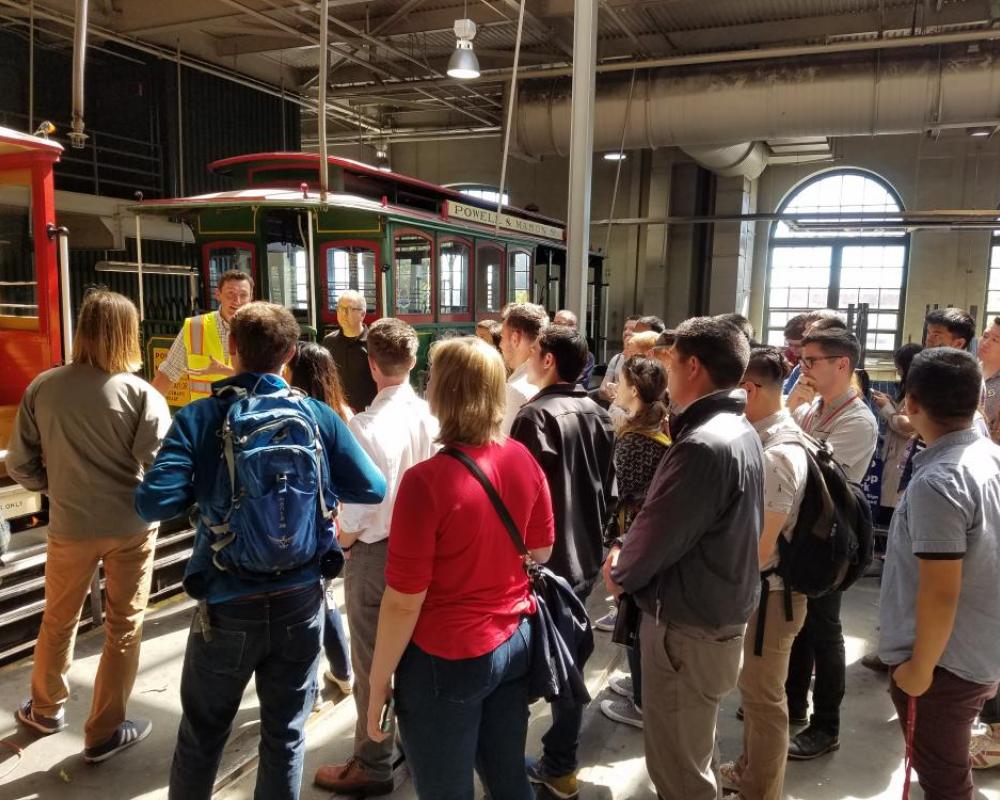 Photo of interns listening to presentation with cable car in background