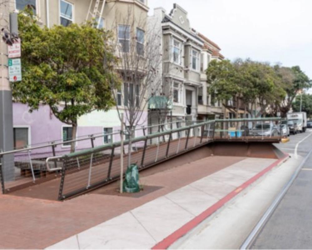 Accessible boarding ramp at street level with trees planted nearby. 