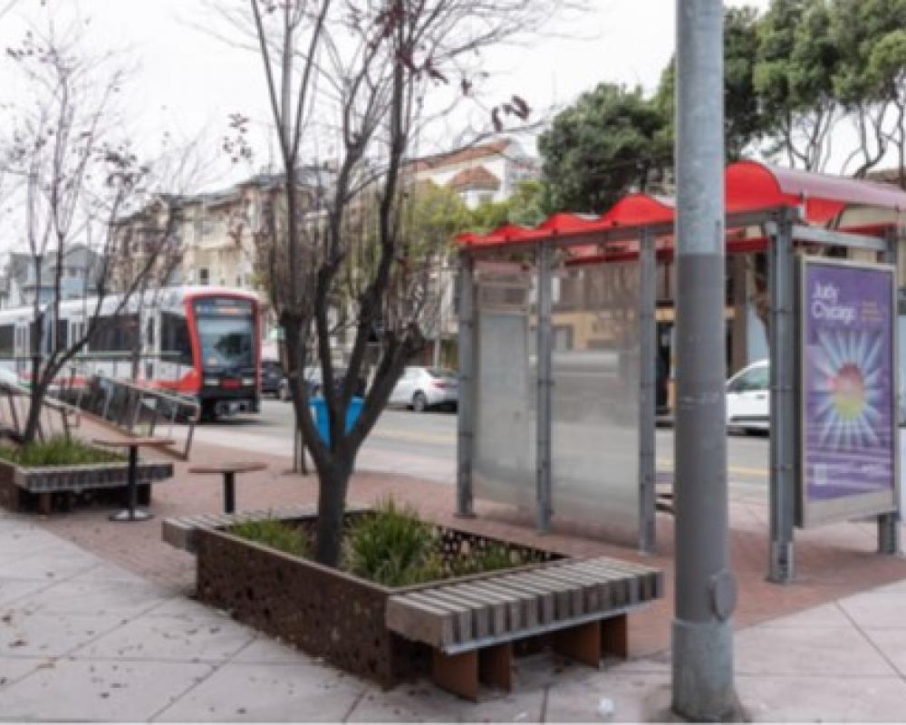 Planters that have benches built in with trees near a transit shelter. 