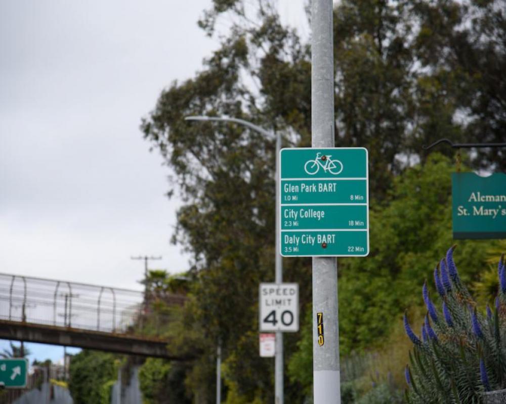 Directional bike signage, 40 MPH sign, and  St. Mary's Park Footbridge