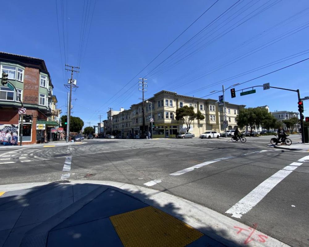 Intersection of Guerrero and 16th streets with cyclists and crossing in crosswalk. Car tire marks prevalent. 