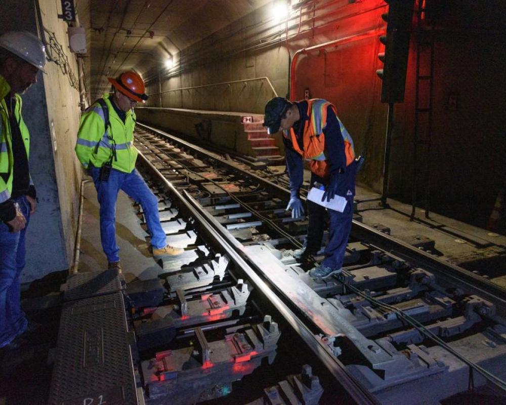 Workers looking at subway tracks and loop cable wire
