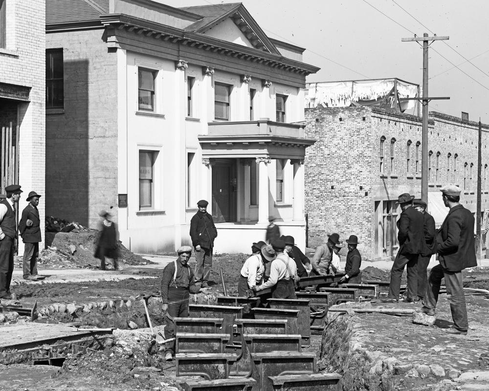 black and white photo of men working on rails in the street