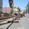 Another length of rail is lifted into place onto steel rollers to be moved north up 4th Street.
