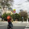 View of two people on bikes using the protected downhill bikeway on Page Street at Laguna Street, facing east toward Downtown