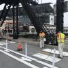 two people wearing yellow safety vests spray painting white paint using stencils in a two-way bikeway with plastic delineators