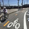 two people riding in a two-way protected bikeway that is marked by bicycle symbols on the roadway