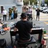 Community members on Page Slow Street stop and listen to a man playing piano in the street