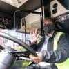 Operator waiving hello at the wheel of a bus
