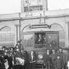 black and white photo of a crowd of people standing in front of a streetcar at the foot of the ferry building