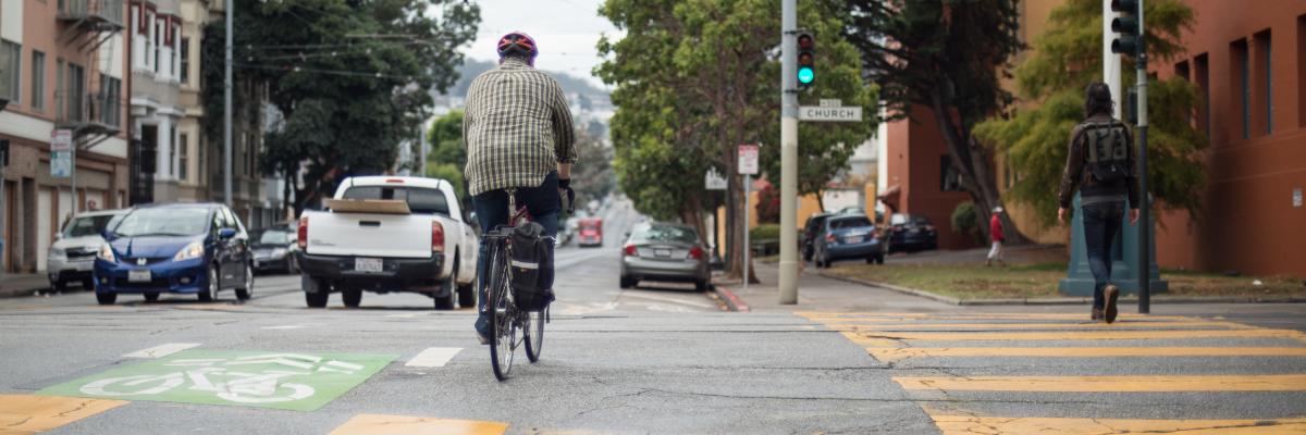 person riding bike across church street on 17th and person walking across in crosswalk