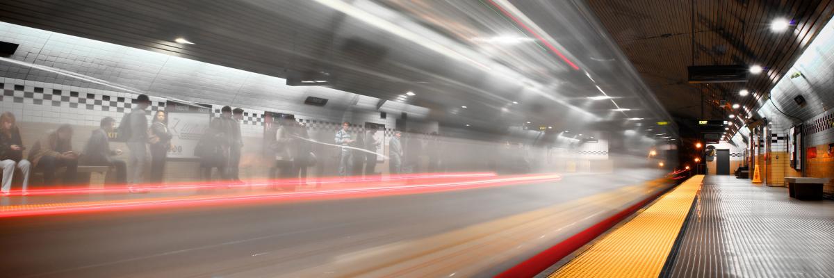 Muni Subway with a train in motion with people on the boarding platforms