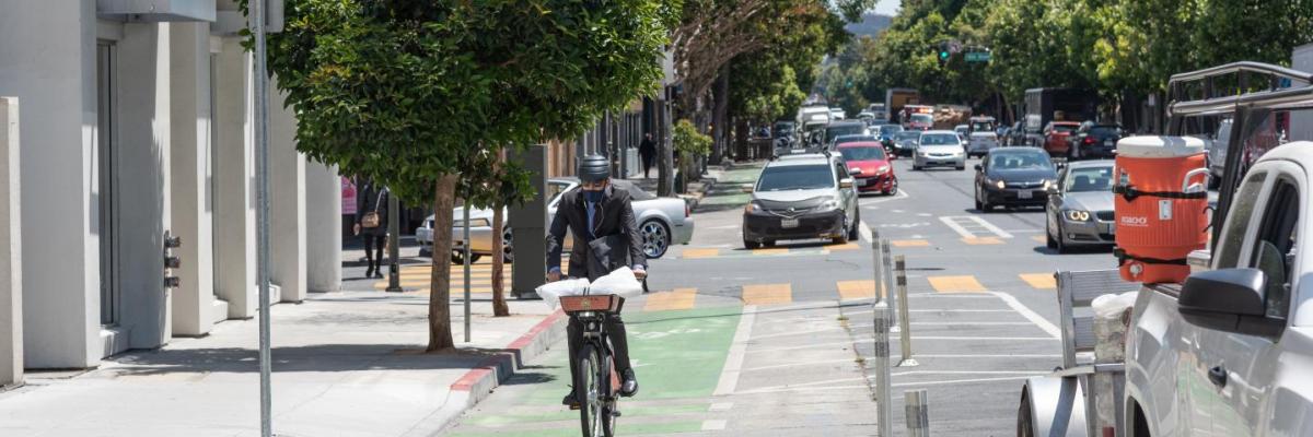 Person riding bikeshare bike in physically separated bike lane