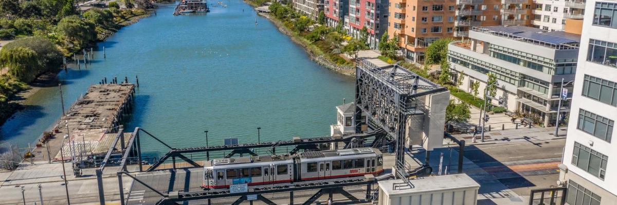 Photo by: Jim Maurer (CC BY-NC-ND 2.0). view of Islais Creek and the 4th street bridge with a Muni train passing by. 