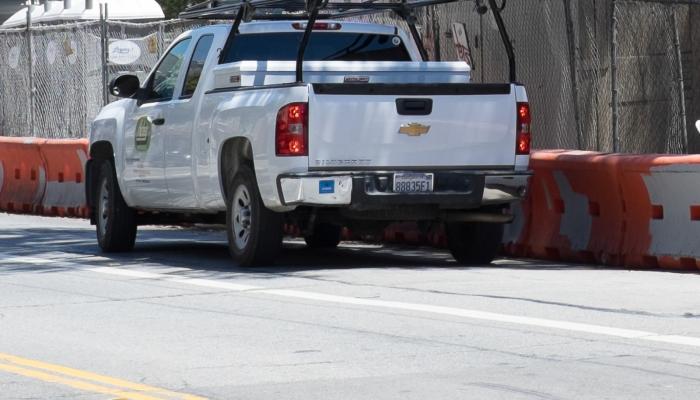 white pickup truck parked outside construction zone with contractor parking permit sticker on bumper