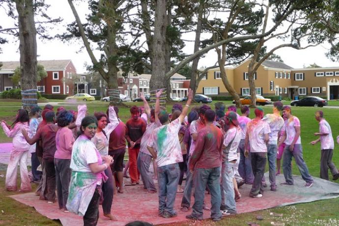 Dozens of people covers in colorful dye in the middle of a park surrounded by trees