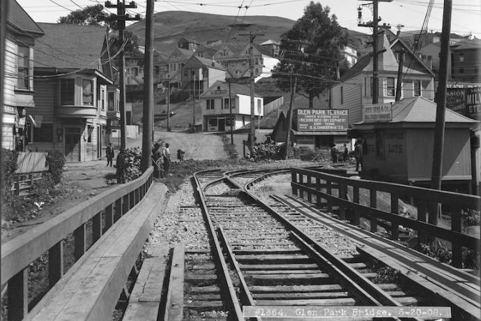 View north on Diamond near Chenery of wooden bridge and streetcar rails, street curving uphill and early 20th century buildings