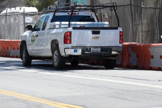 white pickup truck parked outside construction zone with contractor parking permit sticker on bumper