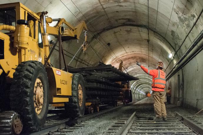 worker directing large machine lifting old track section inside Sunset Tunnel